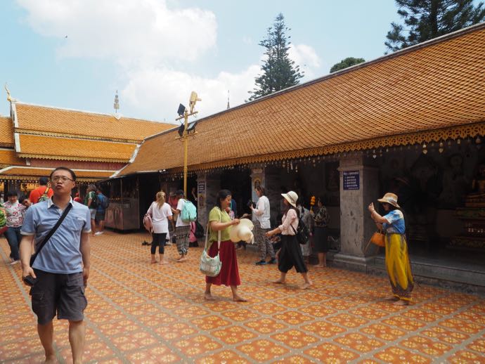 チェンマイの寺院の境内を裸足で歩く人々