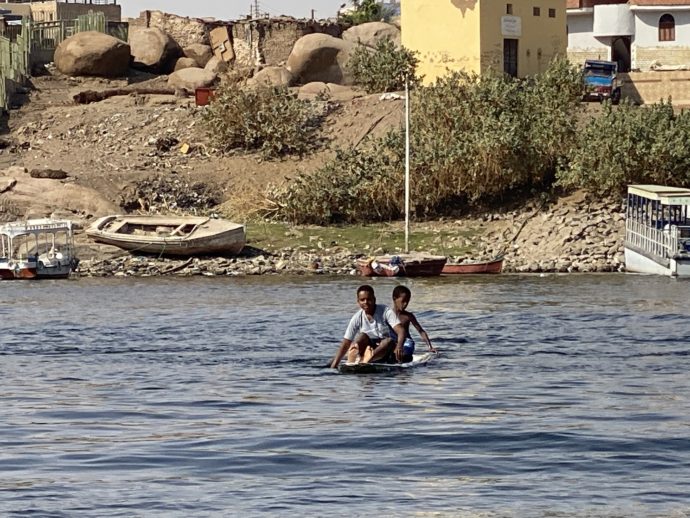 手漕ぎボートでナイル川を渡る少年たち