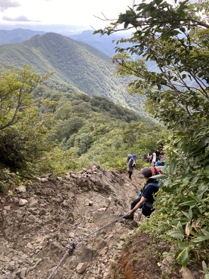 谷川岳の岩場の急斜面に登る人