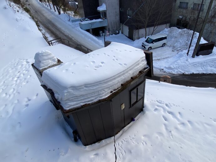 小屋の上の屋根に積もった雪の上についた足跡