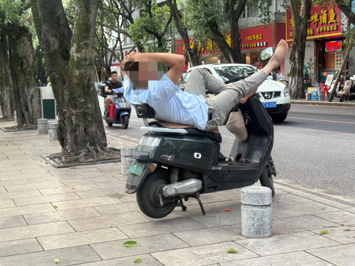 バイクの上で眠る男性
