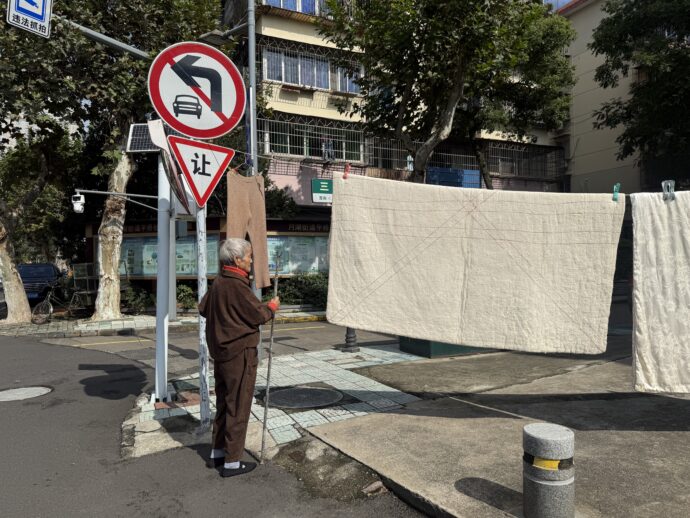シーツを野外に干す女性